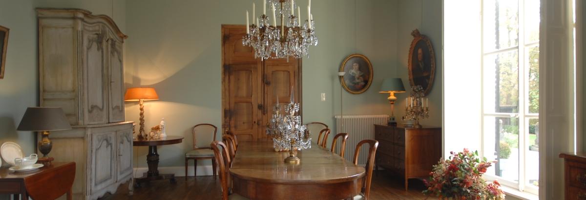 Antieke inrichting in een ruimte met groene muren, wat aansluit op de tuin